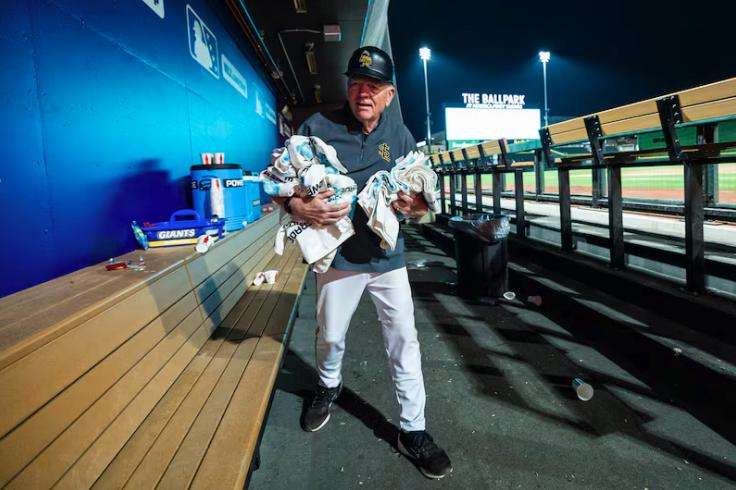 Gene Chidester, 76, a batboy for the Salt Lake Bees, collects discarded towels from the visiting team’s dugout after a Minor League Baseball game between the Bees and the Las Vegas Aviators held at The Ballpark at America First Square in South Jordan on Aug. 5.