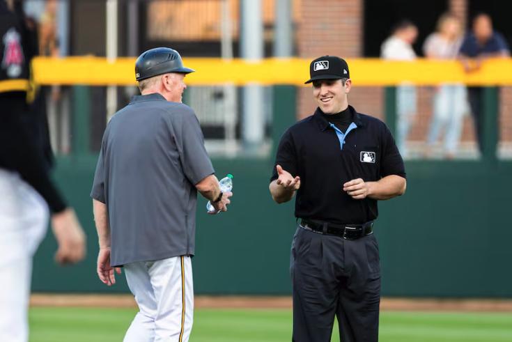 Gene Chidester, 76, a batboy for the Salt Lake Bees, hands a bottle of water to umpire Austin Snow between innings during a Minor League Baseball game between the Bees and the Las Vegas Aviators held at The Ballpark at America First Square in South Jordan on Aug. 5. Batboys are also responsible for keeping the umpires hydrated.