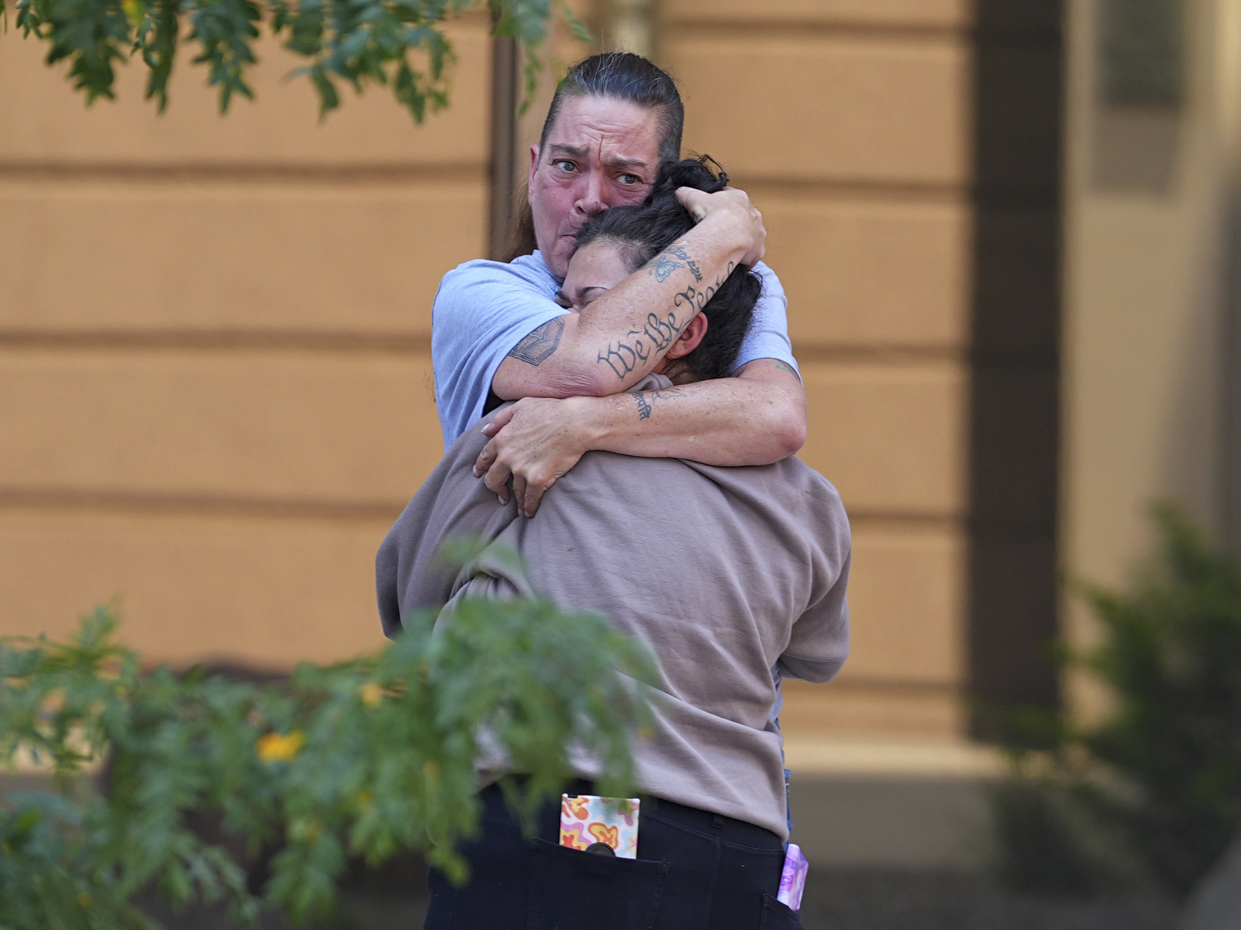 Crystina Page, back, hugs a well-wisher outside the El Paso County Courthouse after a judge ruled against accepting a plea deal in the case of a funeral home owner who stored roughly 189 decomposing bodies in a building Friday, in Colorado Springs, Colo.