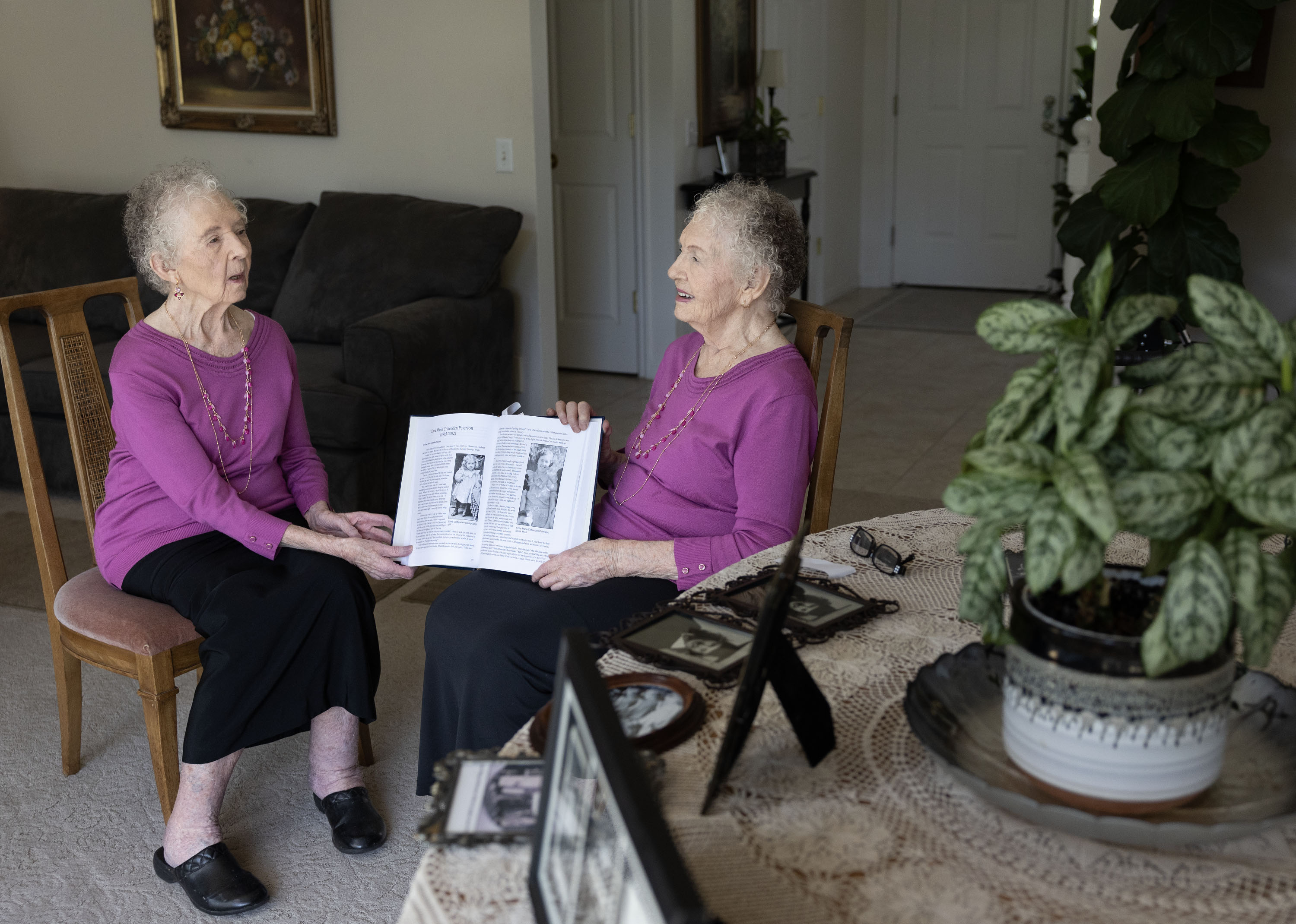 Twin sisters Merla Swensen, left, and Verla Starkey look at a book of their family history at their home in Kaysville on Wednesday.