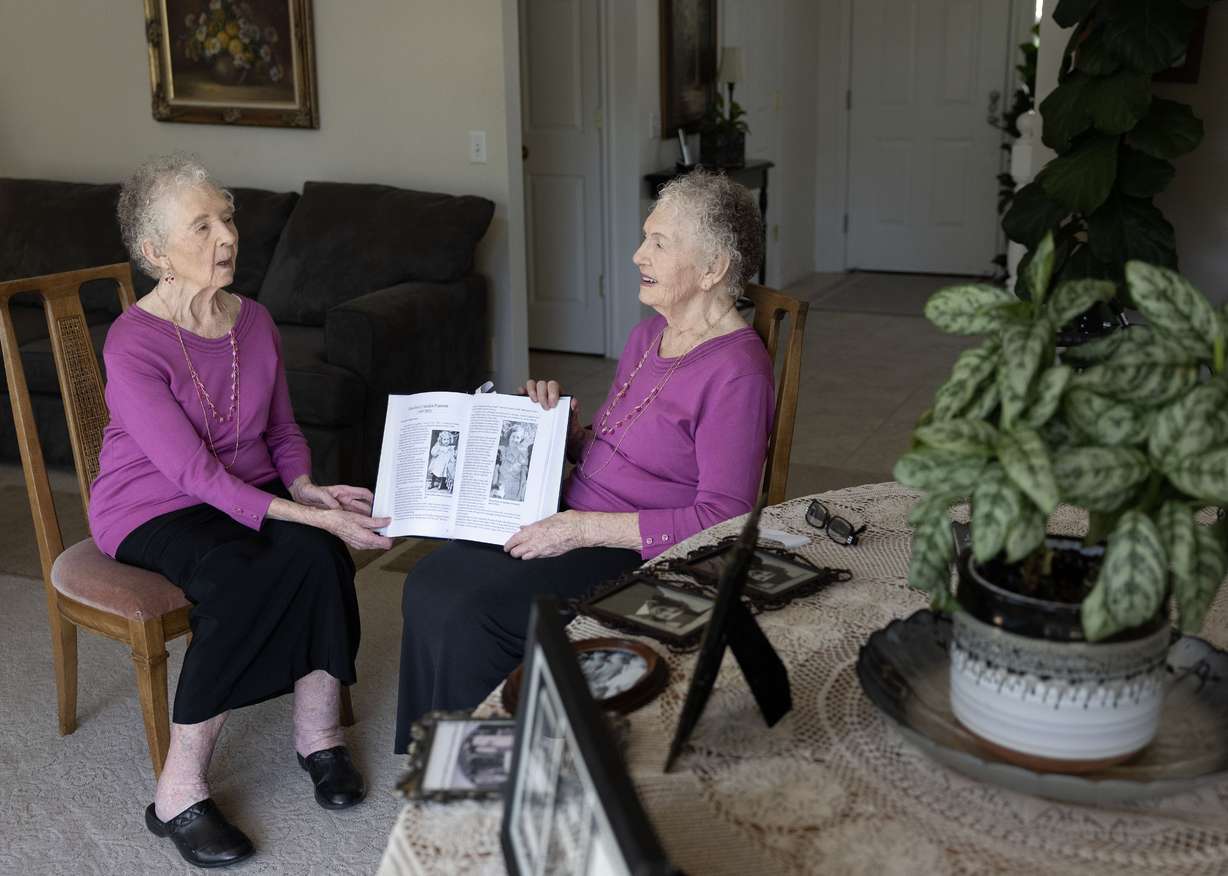 Twin sisters Merla Swensen, left, and Verla Starkey look at a book of their family history at their home in Kaysville on Wednesday.