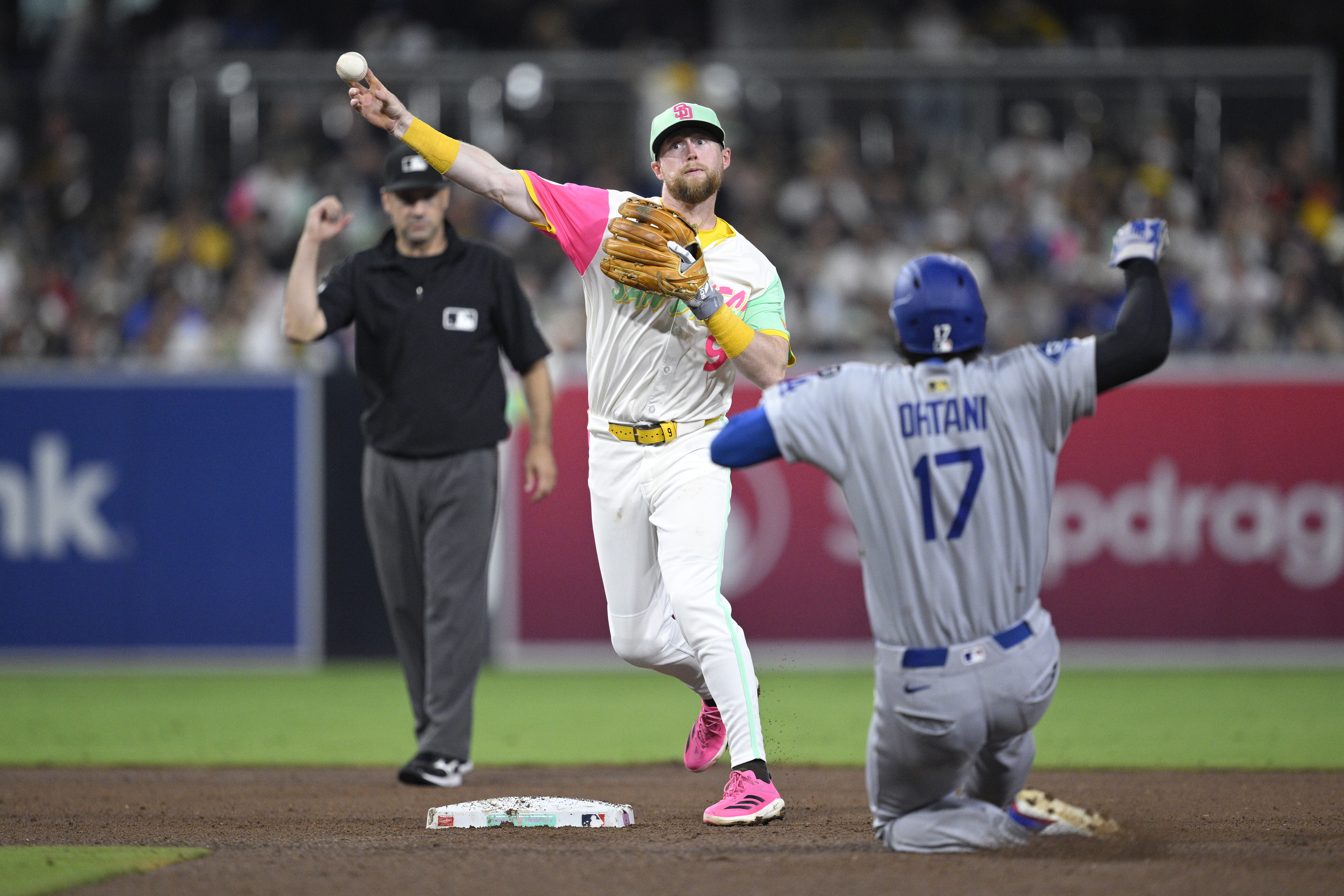 San Diego Padres second baseman Jake Cronenworth, center, throws to first base after forcing out Los Angeles Dodgers' Shohei Ohtani (17) at second base to complete a double play during the sixth inning of a baseball game Friday, Aug. 22, 2025, in San Diego.