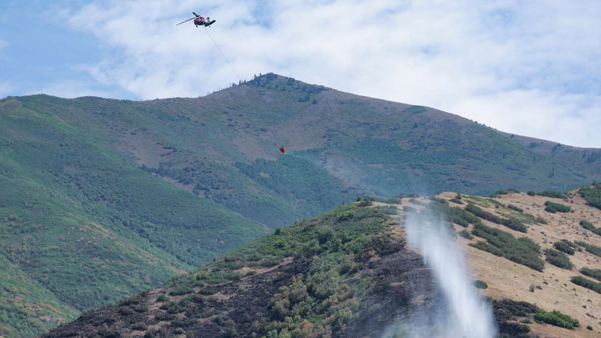 Helicopters drop water on hot spots of a fire that started on Friday Night near Mapleton on Saturday, Aug. 23, 2025.