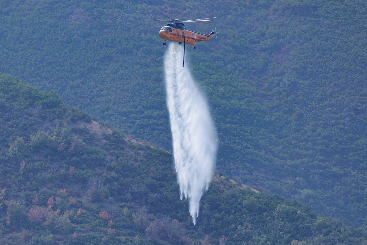 Helicopters drop water on hot spots of a fire that started on Friday Night near Mapleton on Saturday, Aug. 23, 2025.