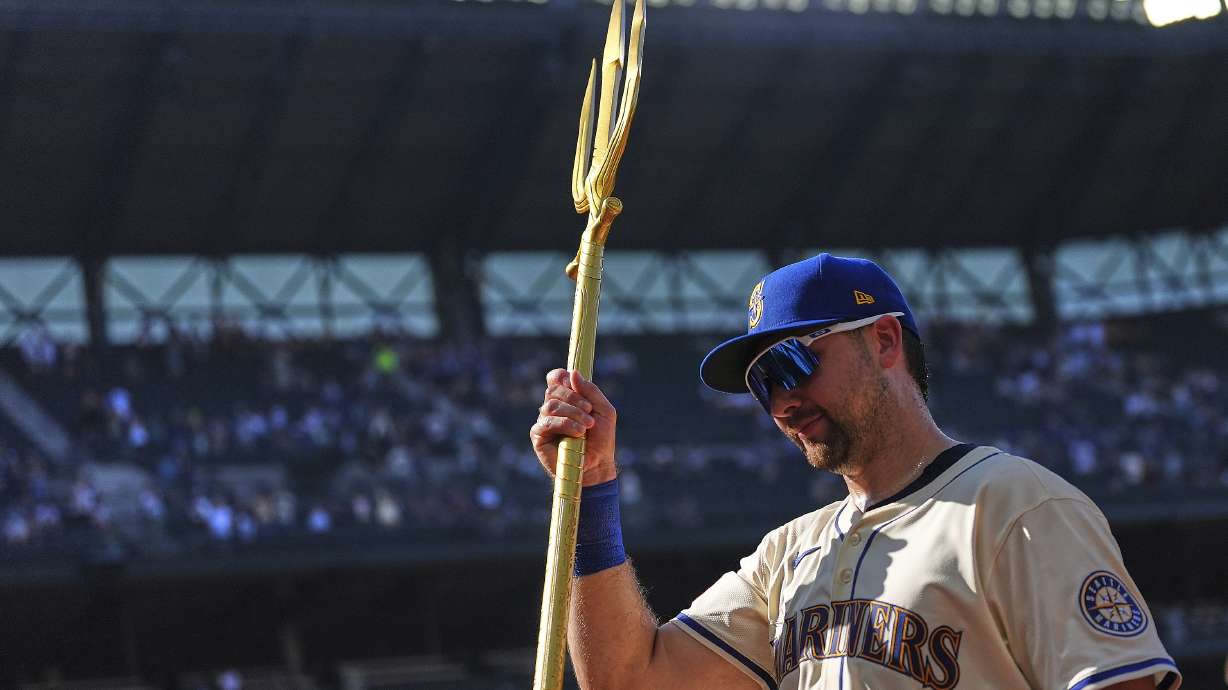 Seattle Mariners catcher Cal Raleigh lifts the trident to celebrate a win over the Athletics in a baseball game Sunday, Aug. 24, 2025, in Seattle.