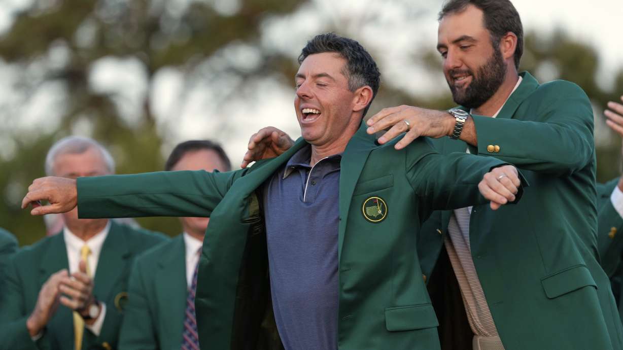FILE - Scottie Scheffler puts the green Jacket on winner, Rory McIlroy, of Northern Ireland, at the Masters golf tournament, Sunday, April 13, 2025, in Augusta, Ga.