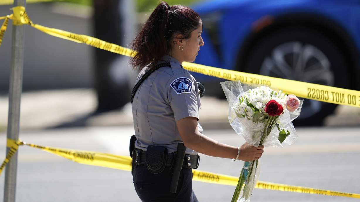 A police officer carries flowers outside the Annunciation Church after a shooting at the school Wednesday in Minneapolis, Minn. Police Chief Brian O'Hara said two children were killed and 17 other people were injured in the shooting.
