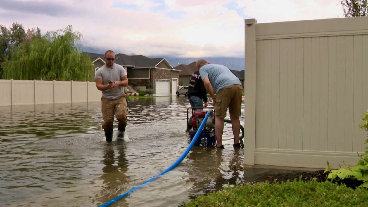 Kyle Browne, left, helps pump water out of a neighborhood in Farr West caused by heavy rainfall on Wednesday.