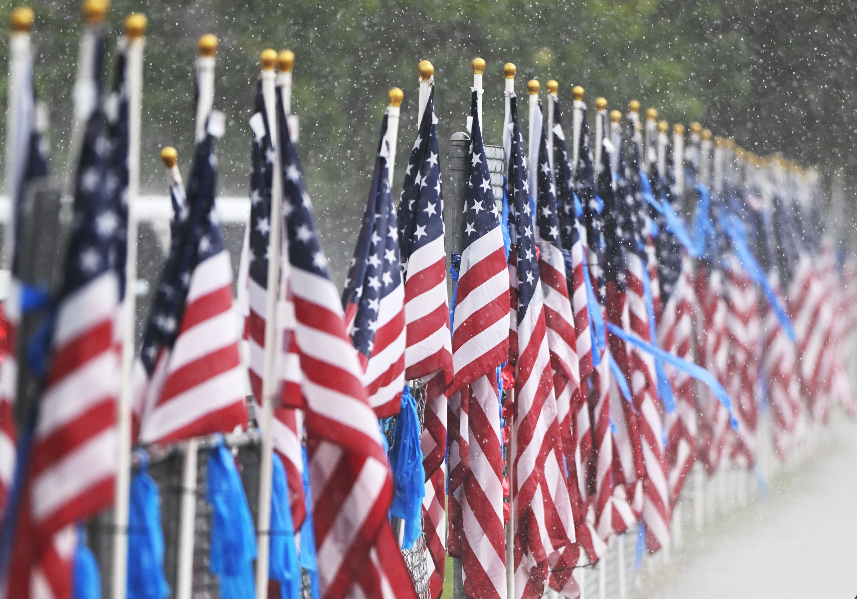 American flags line the road while rain falls as law enforcement agencies and community members gather for a viewing for Tremonton-Garland police officers Eric Estrada and Sgt. Lee Sorensen, at Bear River High School in Garland on Wednesday.
