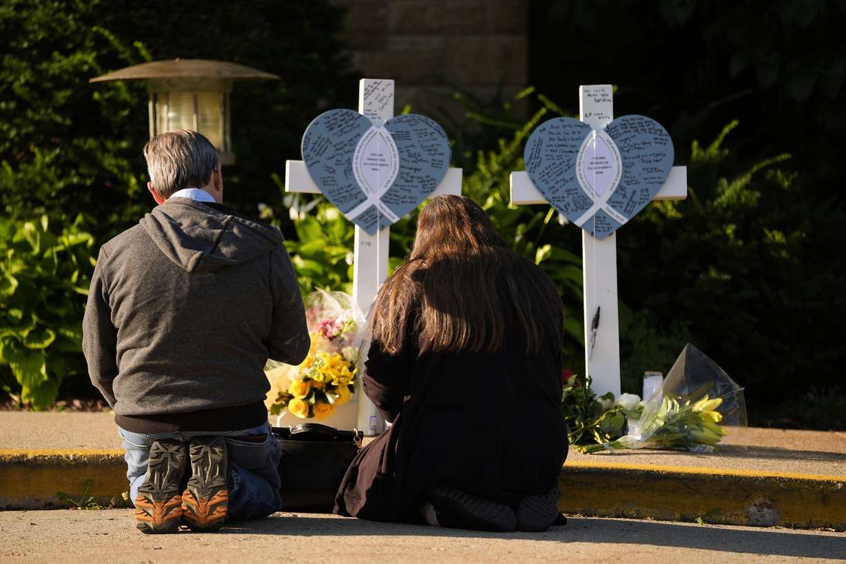 Tim and Katharine Barr kneel and pray at a memorial at Annunciation Catholic Church after Wednesday's school shooting, Thursday, in Minneapolis.