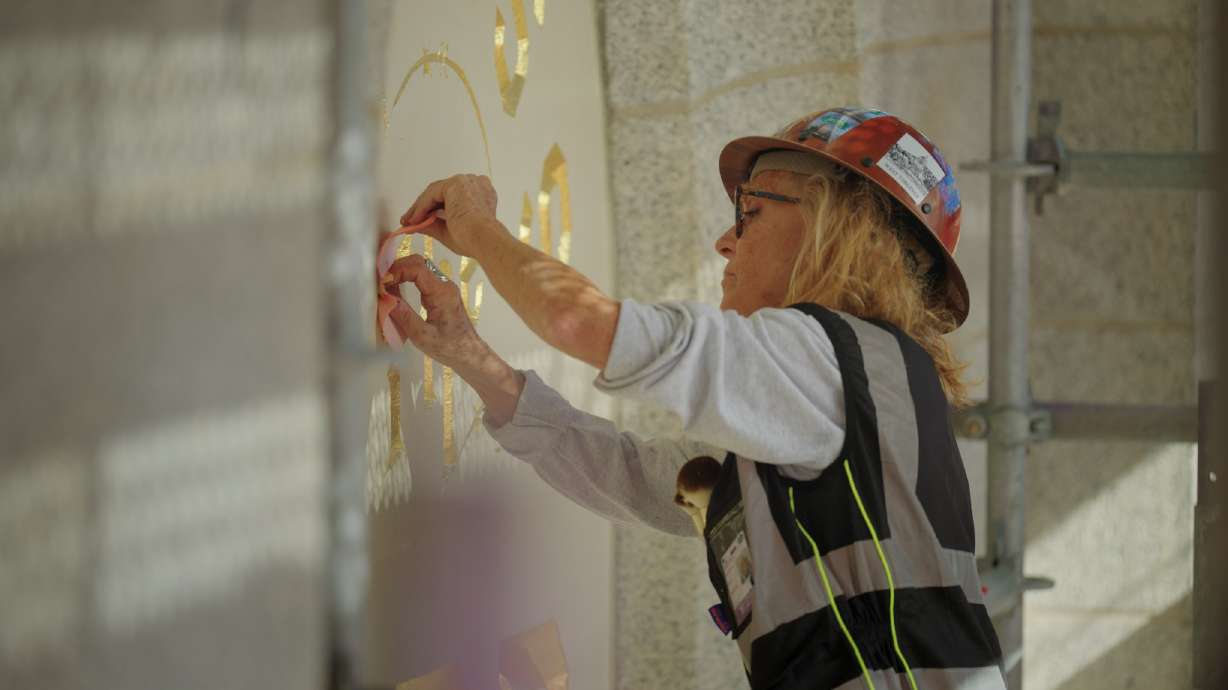 Anne Domenech, an artist with Evergreen, works to restore the "Holiness to the Lord" panel on the Salt Lake Temple of The Church of Jesus Christ of Latter-day Saints on Aug. 18.