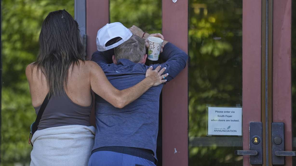 Kristen Neville, left, and Michael Burt cry and embrace each other at the doors of the Annunciation Catholic Church after Wednesday's school shooting, Thursday, in Minneapolis, Minn.