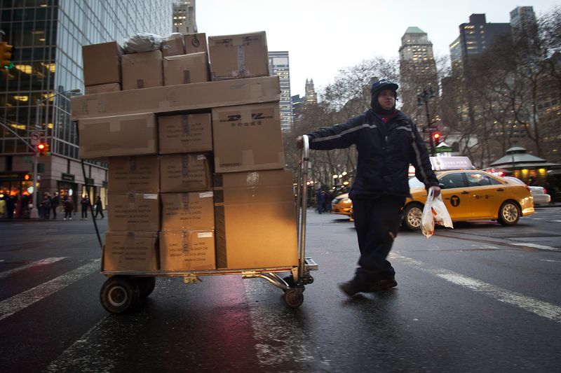 A delivery person wheels a trolley full of packages across 42nd Street in New York, Dec. 2, 2014.