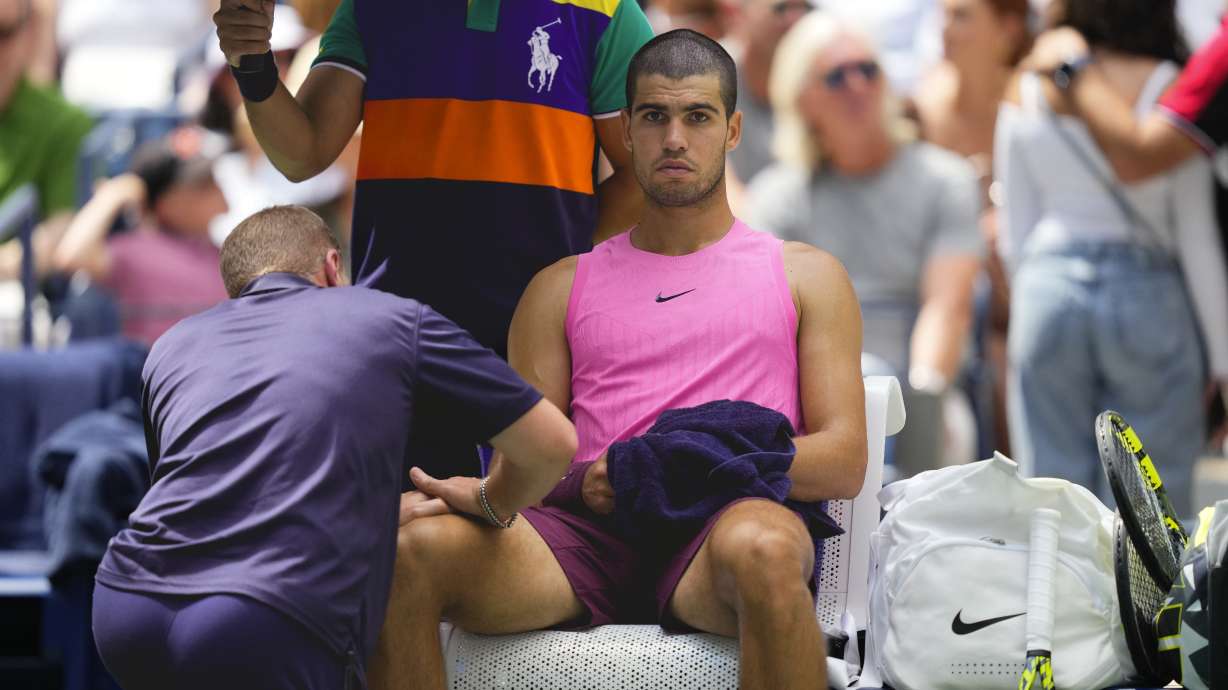 A trainer works on Carlos Alcaraz, of Spain, during a medical timeout in the second set against Luciano Darderi, of Italy, during the third round of the U.S. Open tennis championships, Friday, Aug. 29, 2025, in New York.