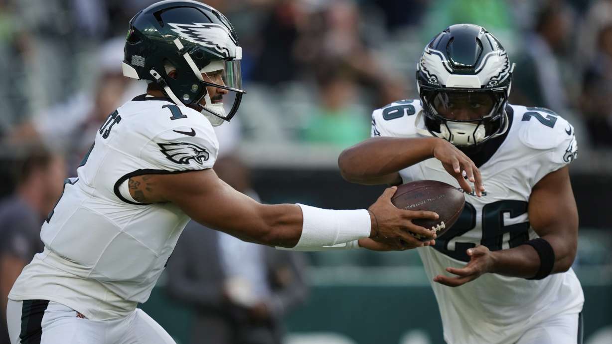 Philadelphia Eagles quarterback Jalen Hurts (1) hands off to Eagles running back Saquon Barkley (26) during warm ups before an NFL preseason football game against the Cincinnati Bengals on Thursday, Aug. 7, 2025, in Philadelphia.