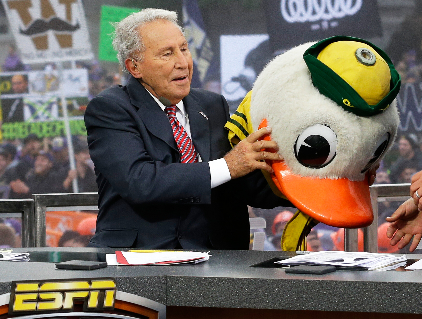 FILE - ESPN College GameDay host Lee Corso puts on the mascot head of the Oregon Ducks, Oct. 12, 2013, during College GameDay's broadcast from Red Square on the University of Washington campus in Seattle. 
