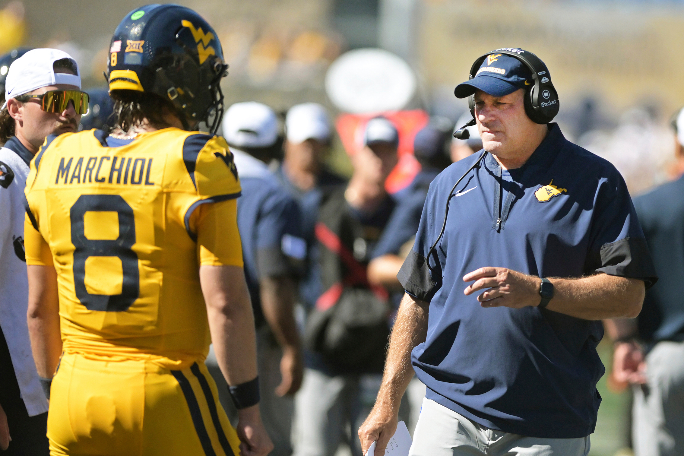 West Virginia coach Rich Rodriguez talks to quarterback Nicco Marchiol during the first half an NCAA college football game against Robert Morris, Saturday, Aug. 30, 2025, in Morgantown, W.Va. 