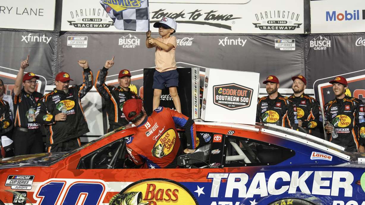 Chase Briscoe (19) climbs out of his car as his son Brooks, top, waves the checked flag in Victory Lane after winning a NASCAR Cup Series auto race at Darlington Raceway, Sunday, Aug. 31, 2025, in Darlington, S.C.