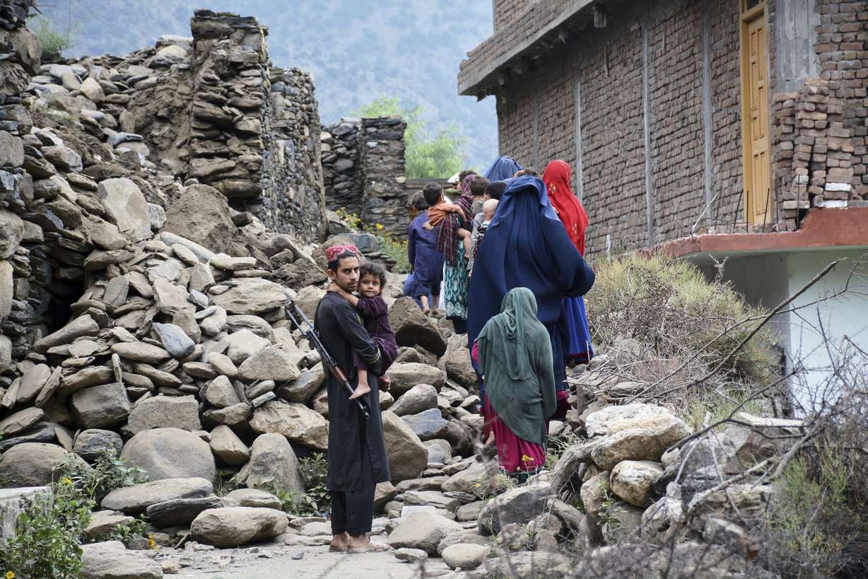 Local residents walk by a house destroyed by an earthquake that killed many people and destroyed villages in eastern Afghanistan, in Mazar Dara, Kunar province, Afghanistan, Monday.