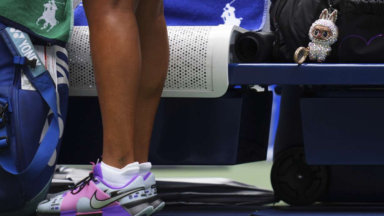 A Labubu doll sits near Naomi Osaka, of Japan, before her match against Coco Gauff, of the United States, during the fourth round of the US Open tennis championships, Monday, Sept. 1, 2025, in New York.