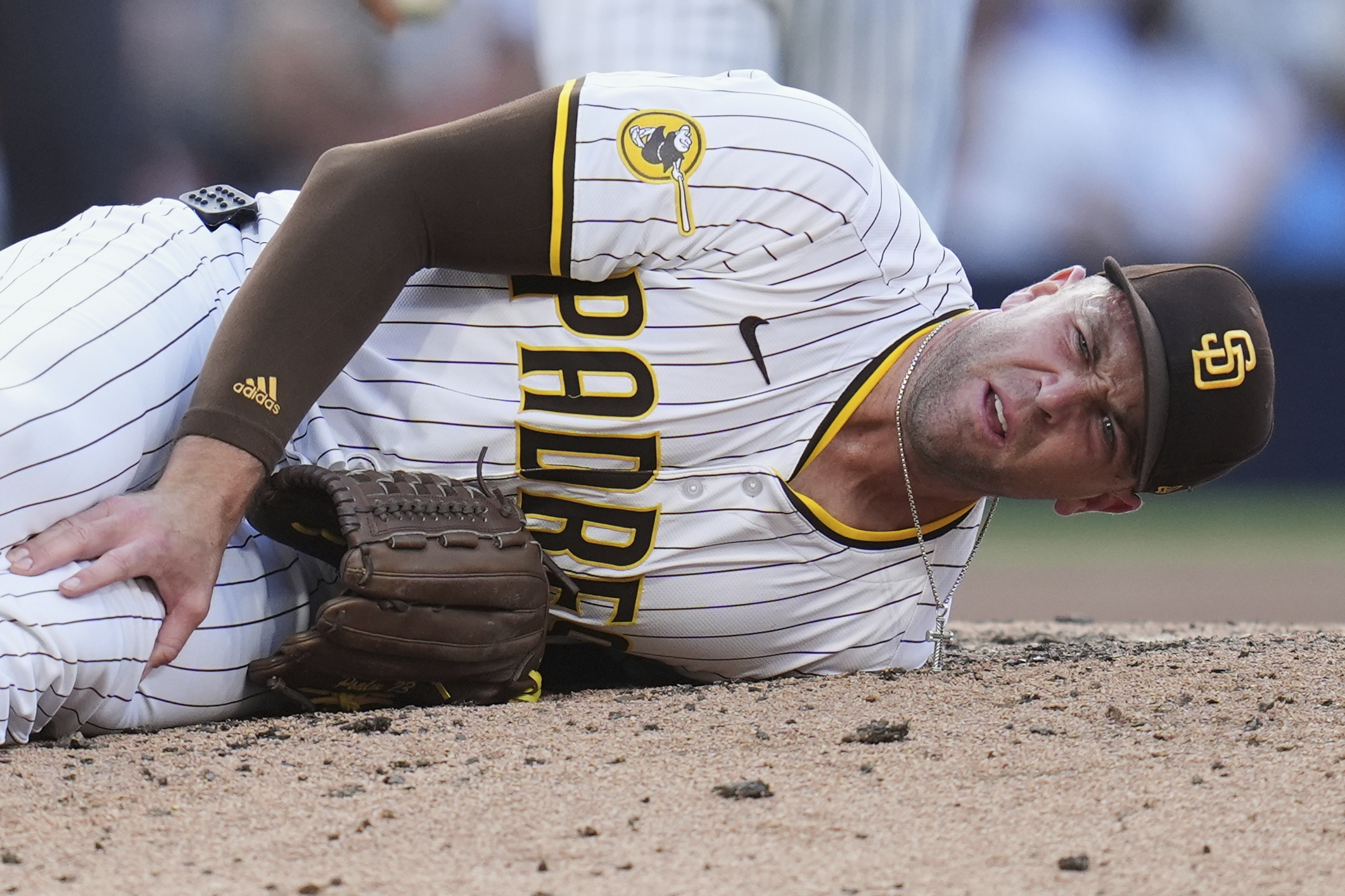 San Diego Padres relief pitcher Jason Adam holds his leg after falling with an injury during the seventh inning of a baseball game against the Baltimore Orioles Monday, Sept. 1, 2025, in San Diego. 