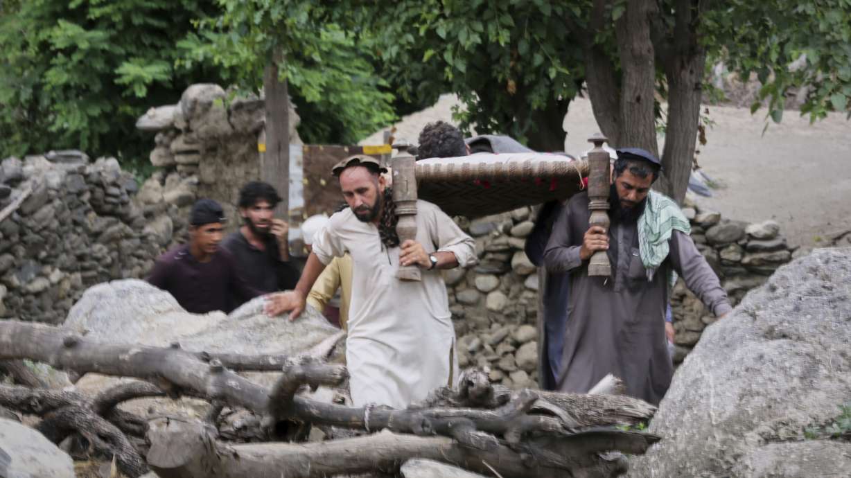 An injured person is carried to a military helicopter that landed to evacuate injured victims of an earthquake that killed many people and destroyed villages in eastern Afghanistan, in Mazar Dara, Kunar province, Monday.