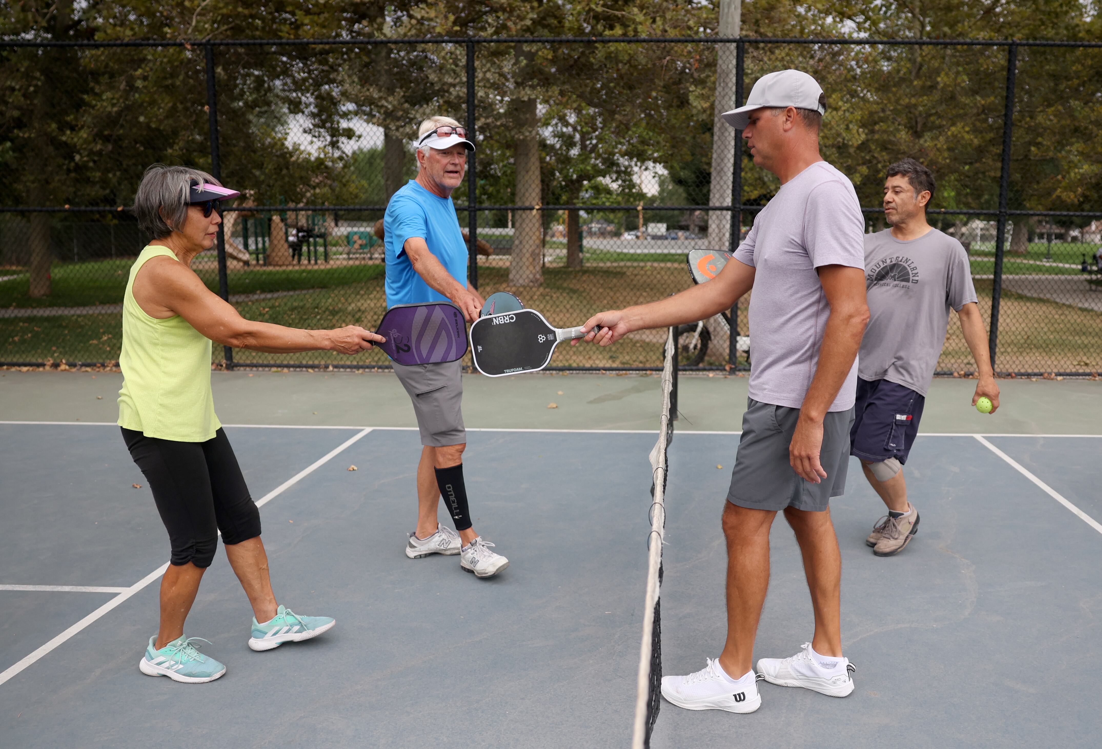 Brenda Koga, Lon Stalsberg, Chad Oberson and Johnny Garcia tap paddles at Fairmont Park in Salt Lake City on Aug. 26. Koga said the social aspect of the game keeps her moving.