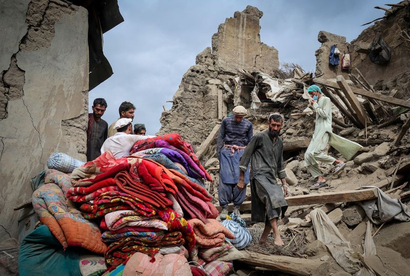 Afghan men walk on the rubble of a damaged house following a deadly magnitude-6 earthquake that struck Afghanistan on Sunday, in Mazar Dara, Kunar province, Afghanistan, Tuesday.