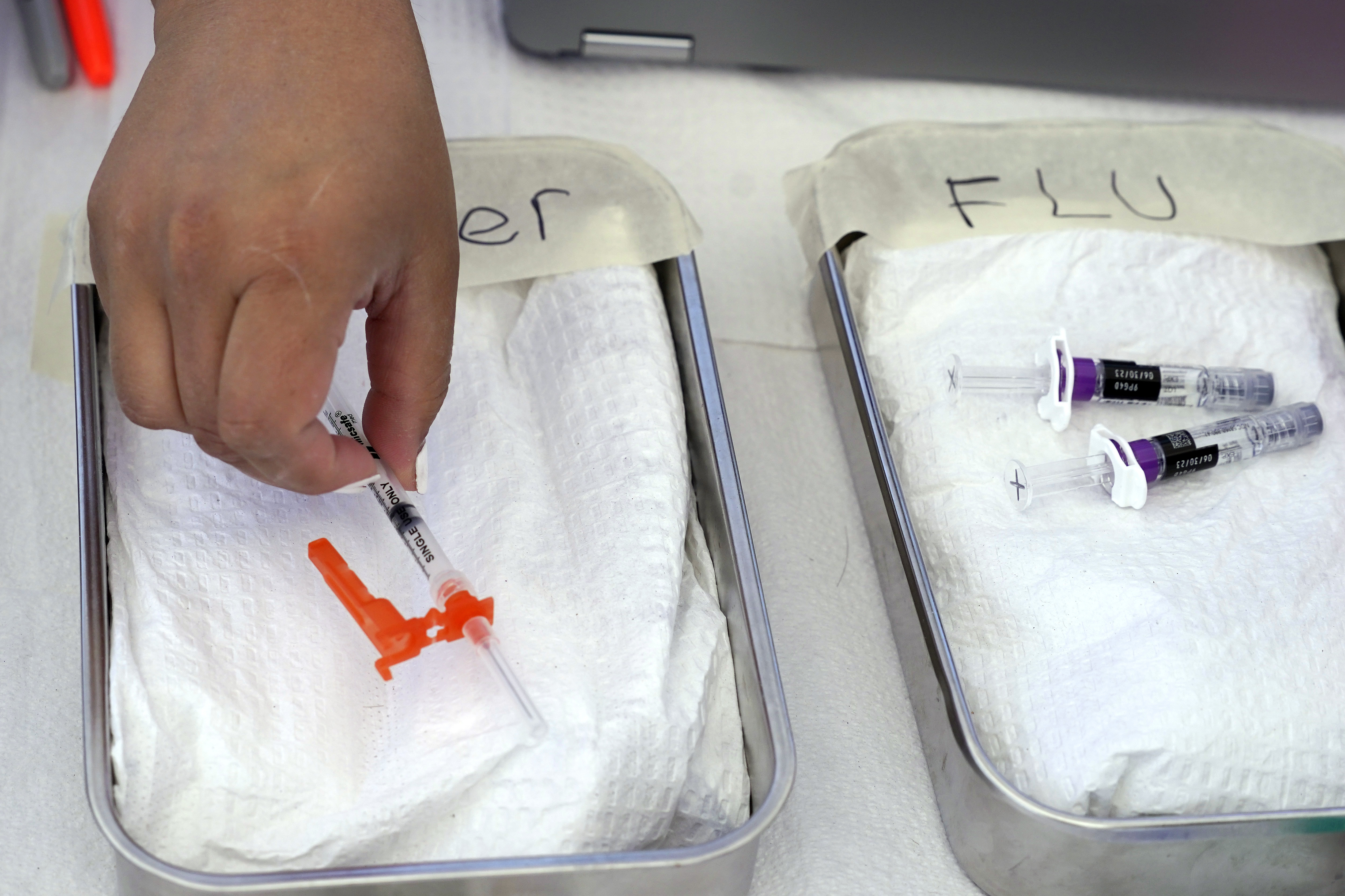 A COVID vaccine is readied as a flu vaccine sits nearby at the L.A. Care and Blue Shield of California Promise Health Plans' Community Resource Center, Oct. 28, 2022, in Lynwood, Calif. Top doctors offered guidance on getting the vaccines this fall.