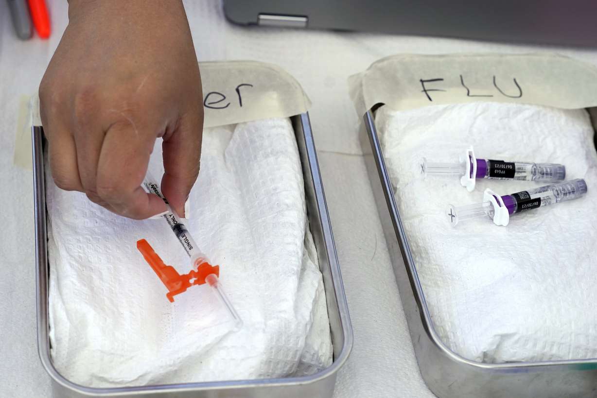 A COVID vaccine is readied as a flu vaccine sits nearby at the L.A. Care and Blue Shield of California Promise Health Plans' Community Resource Center, Oct. 28, 2022, in Lynwood, Calif. Top doctors offered guidance on getting the vaccines this fall.