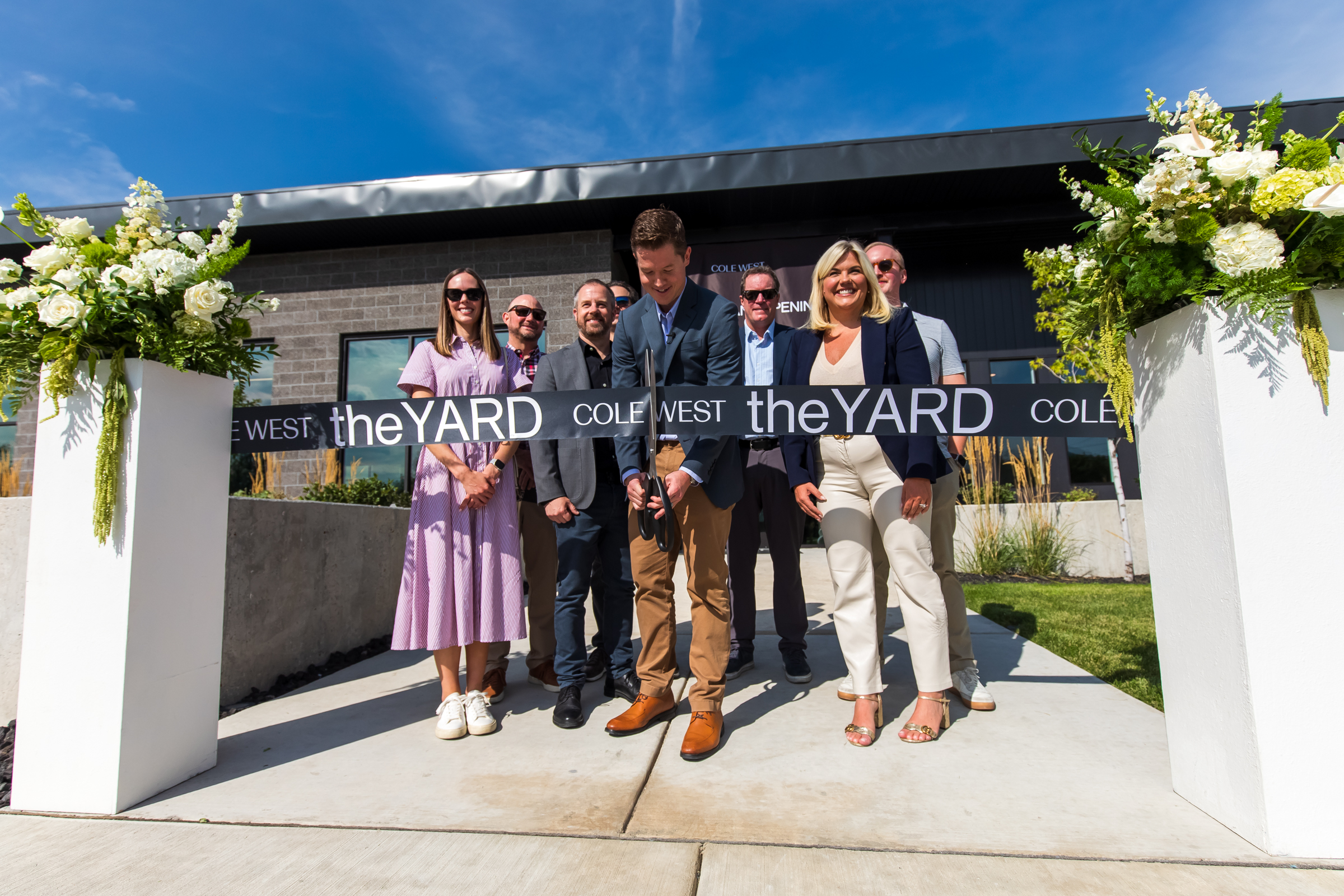 Walker Wood, vice president of development for Cole West, surrounded by other project officials and dignitaries, cuts a ribbon to signal the opening of TheYard in Salt Lake City on Thursday