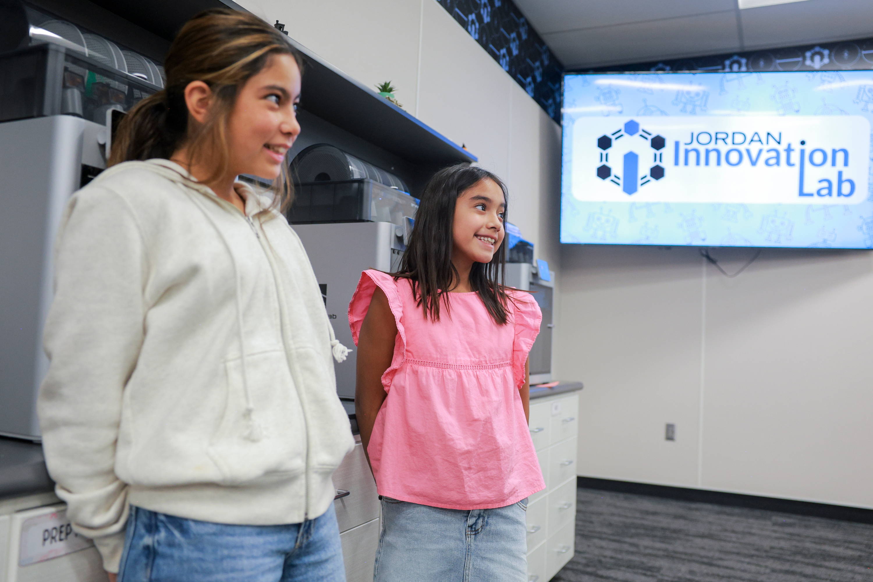 Mila Levine, left, and Diana Nieves, right, speak with a teacher while waiting for their 3D prints to finish in the Jordan Innovation Lab at Juniper Elementary School in Herriman on Friday.