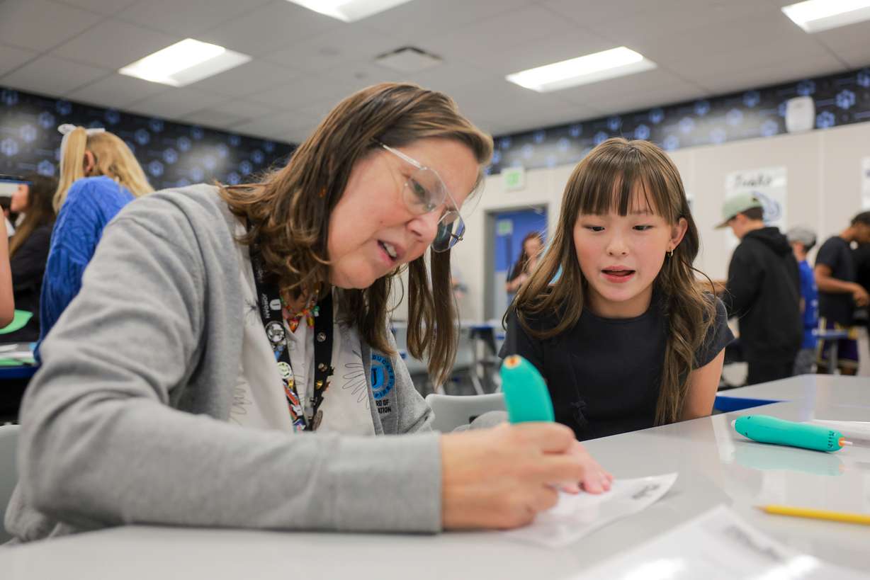 Juniper Elementary student Mia Stobbe, right, teaches Jordan School Board member Lisa Dean, left, how to use a 3D printing pen in the Jordan Innovation Lab at Juniper Elementary School in Herriman on Friday.