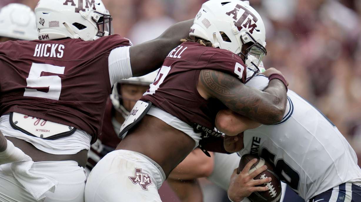 Texas A&M defensive tackle DJ Hicks (5) and defensive end Cashius Howell (9) sack Utah State quarterback Bryson Barnes (16) during the second quarter of an NCAA college football game Saturday, Sept. 6, 2025, in College Station, Texas.