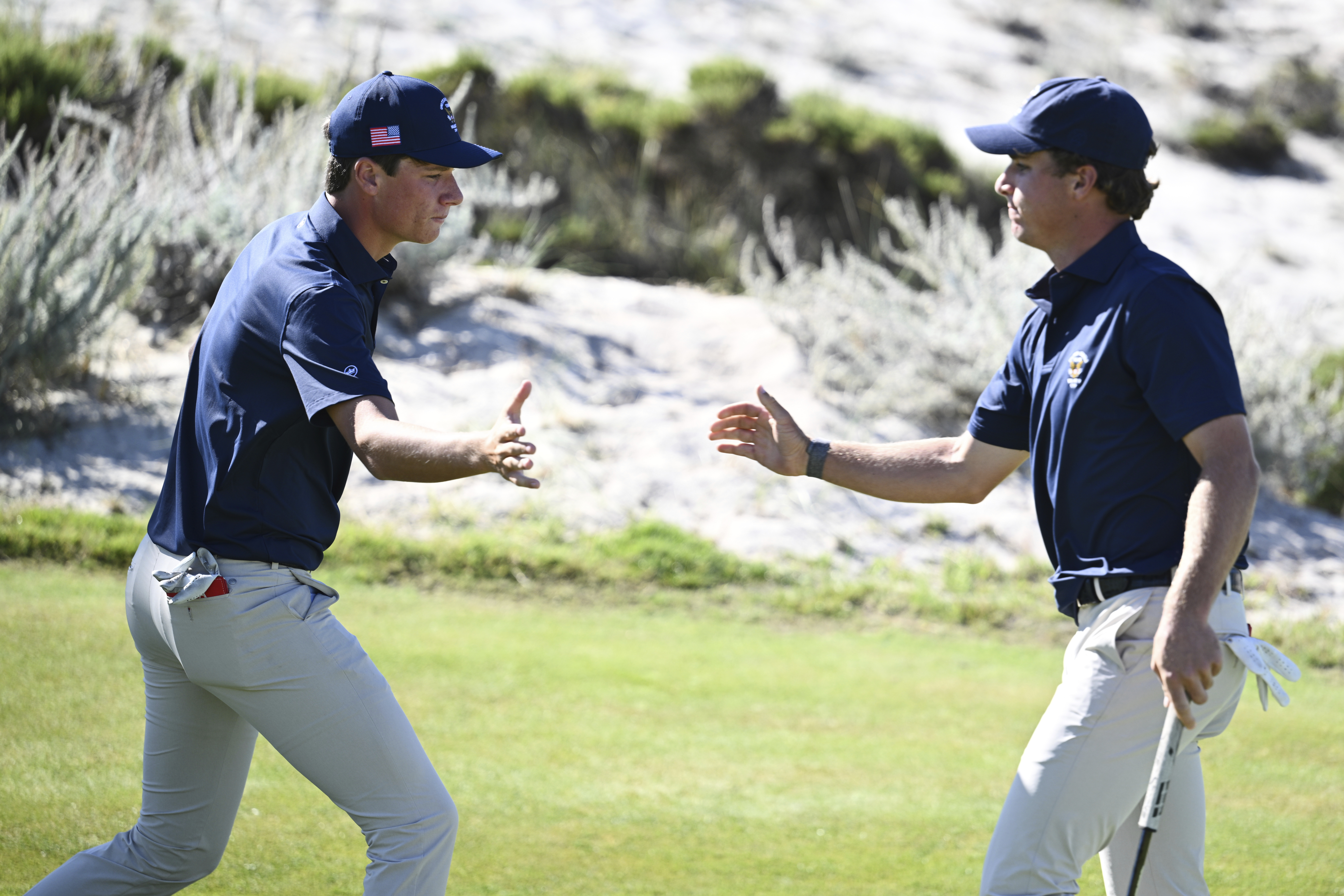 The USA team's Mason Howell, left, shakes hands with Jacob Modleski during Walker Cup golf matches against the Great Britain and Ireland team at Cypress Point Club on Sunday, Sept. 7, 2025, in Pebble Beach, Calif. 