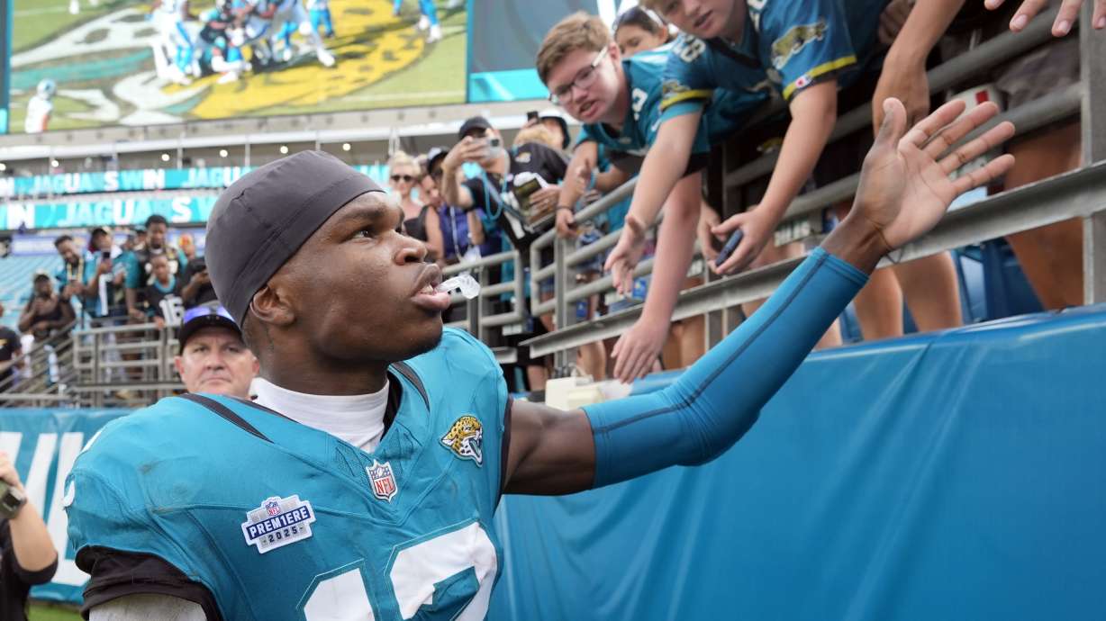 Jacksonville Jaguars wide receiver Travis Hunter (12) signs greets fans after an NFL football game against the Carolina Panthers, Sunday, Sept. 7, 2025, in Jacksonville, Fla.