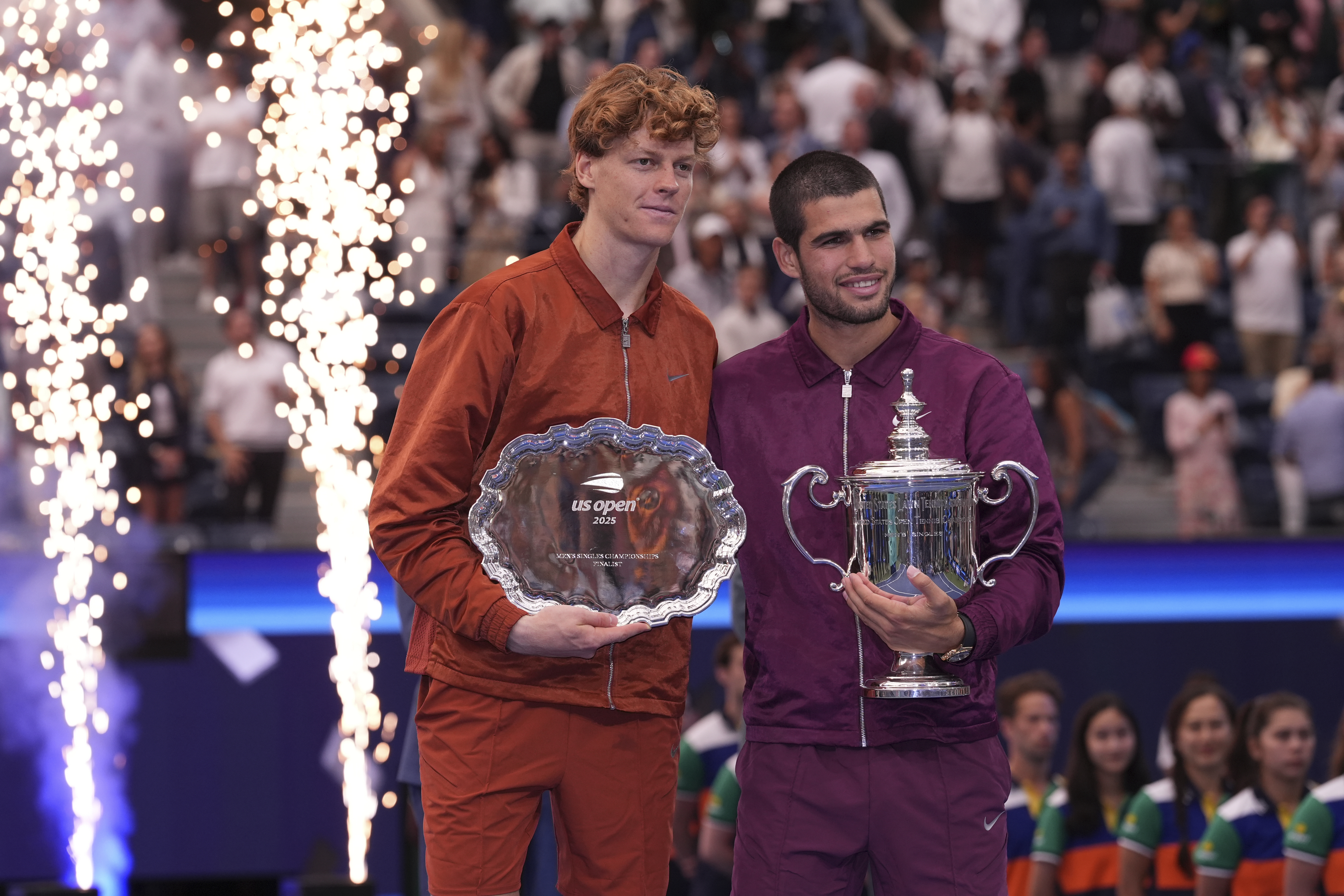 Jannik Sinner, of Italy, left, and Carlos Alcaraz, of Spain, right, hold their trophies after Alcaraz defeated Sinner to win the men's singles final of the U.S. Open tennis championships, Sunday, Sept. 7, 2025, in New York.