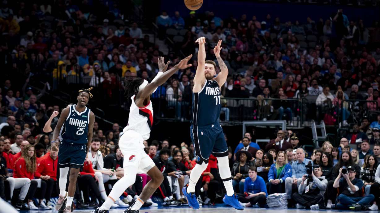 FILE - Dallas Mavericks guard Luka Doncic (77) heaves a shot from half court over Portland Trail Blazers forward Jerami Grant (9) as the buzzer sounds in the first half of an NBA basketball game in Dallas, Dec. 16, 2022.