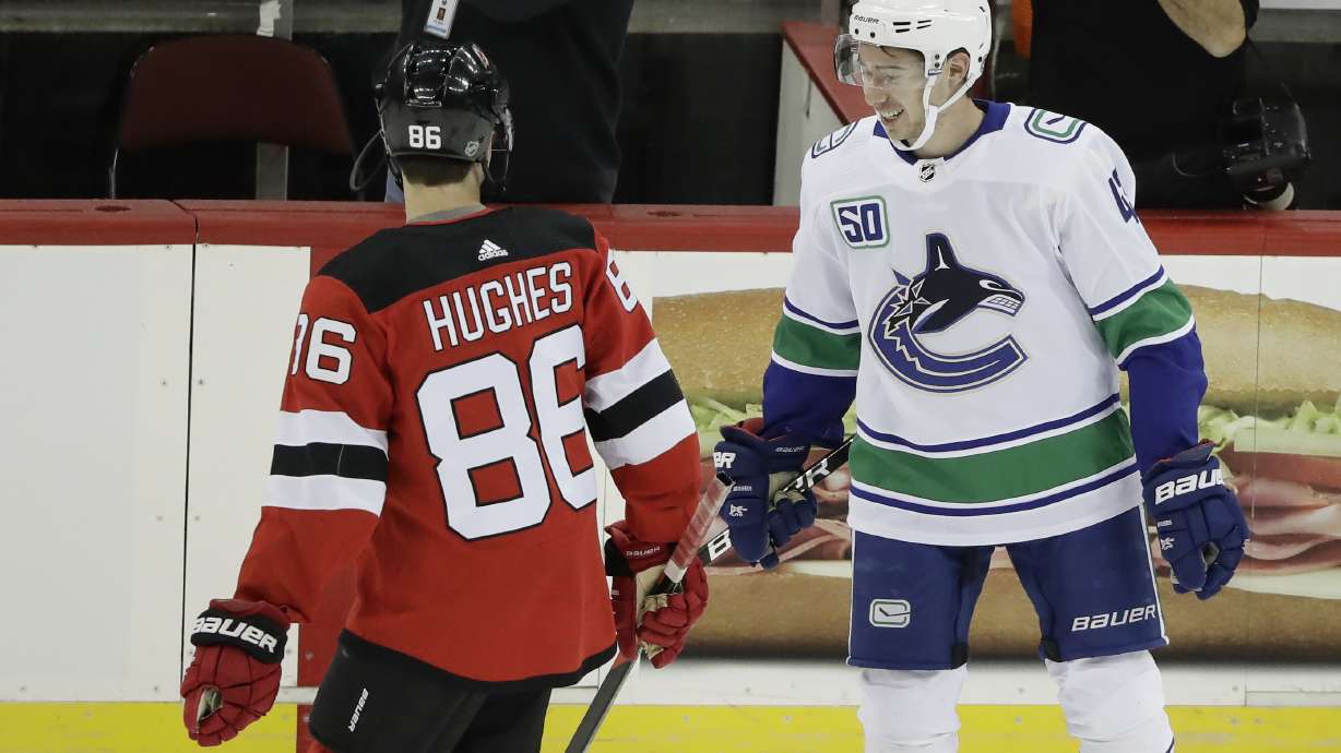 FILE - Vancouver Canucks' Quinn Hughes, right, talks to his brother New Jersey Devils' Jack Hughes, left, before of an NHL hockey game Saturday, Oct. 19, 2019, in Newark, N.J. The Devils won 1-0.
