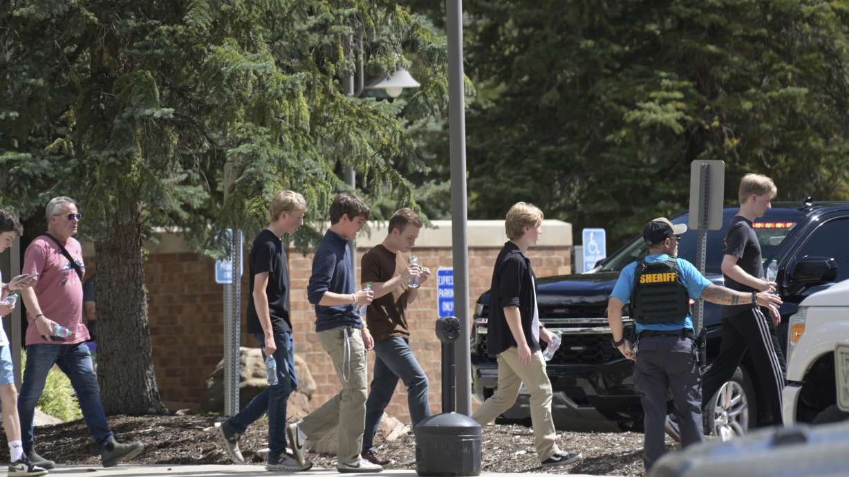 Students board a bus amid heavy police presence at the Evergreen Library after a shooting Wednesday, in Evergreen, Colo. A student is dead after shooting two of his peers, and then himself.