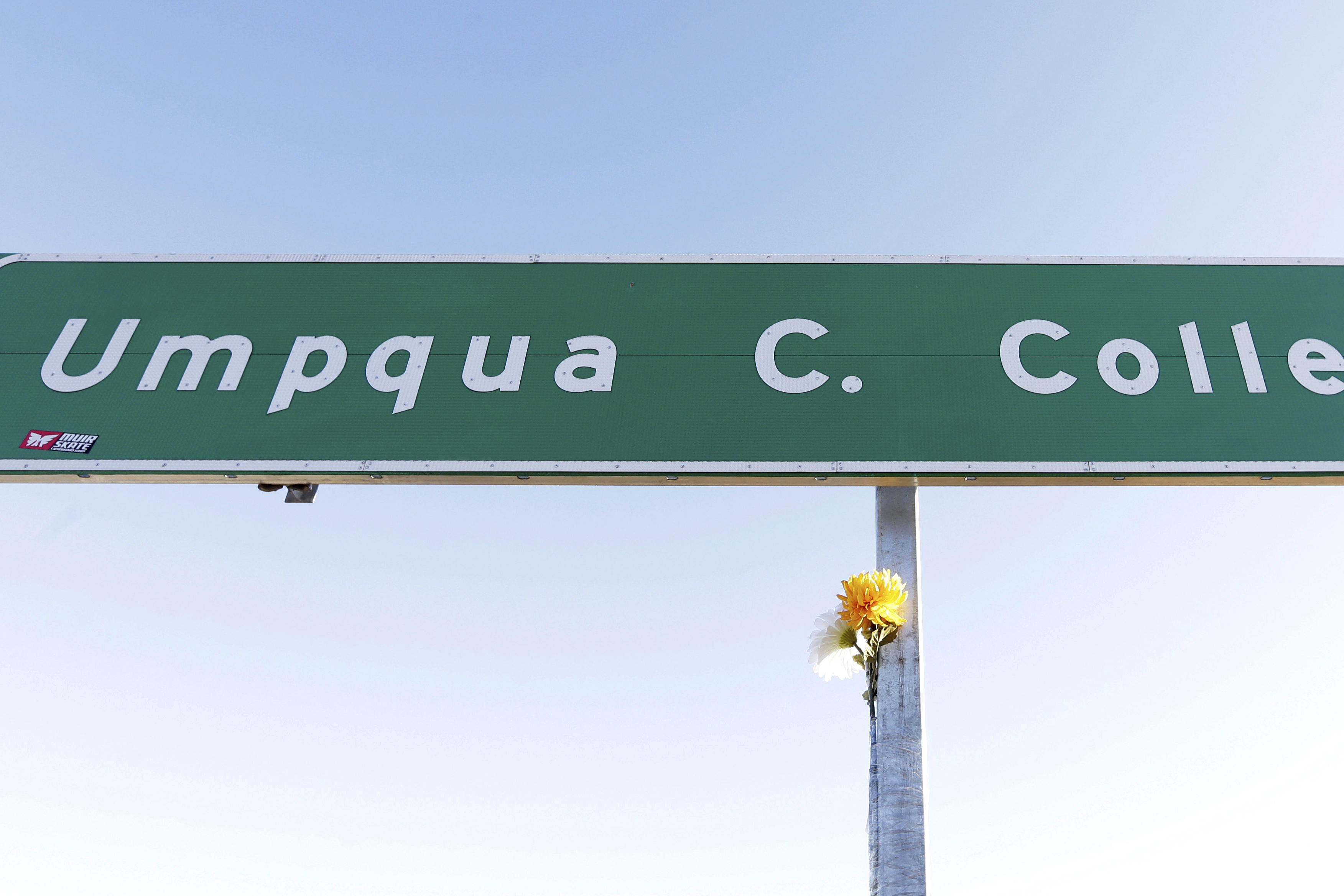 FILE - A flower is posted on a direction sign to Umpqua Community College, Oct. 2, 2015, in Roseburg, Ore. 
