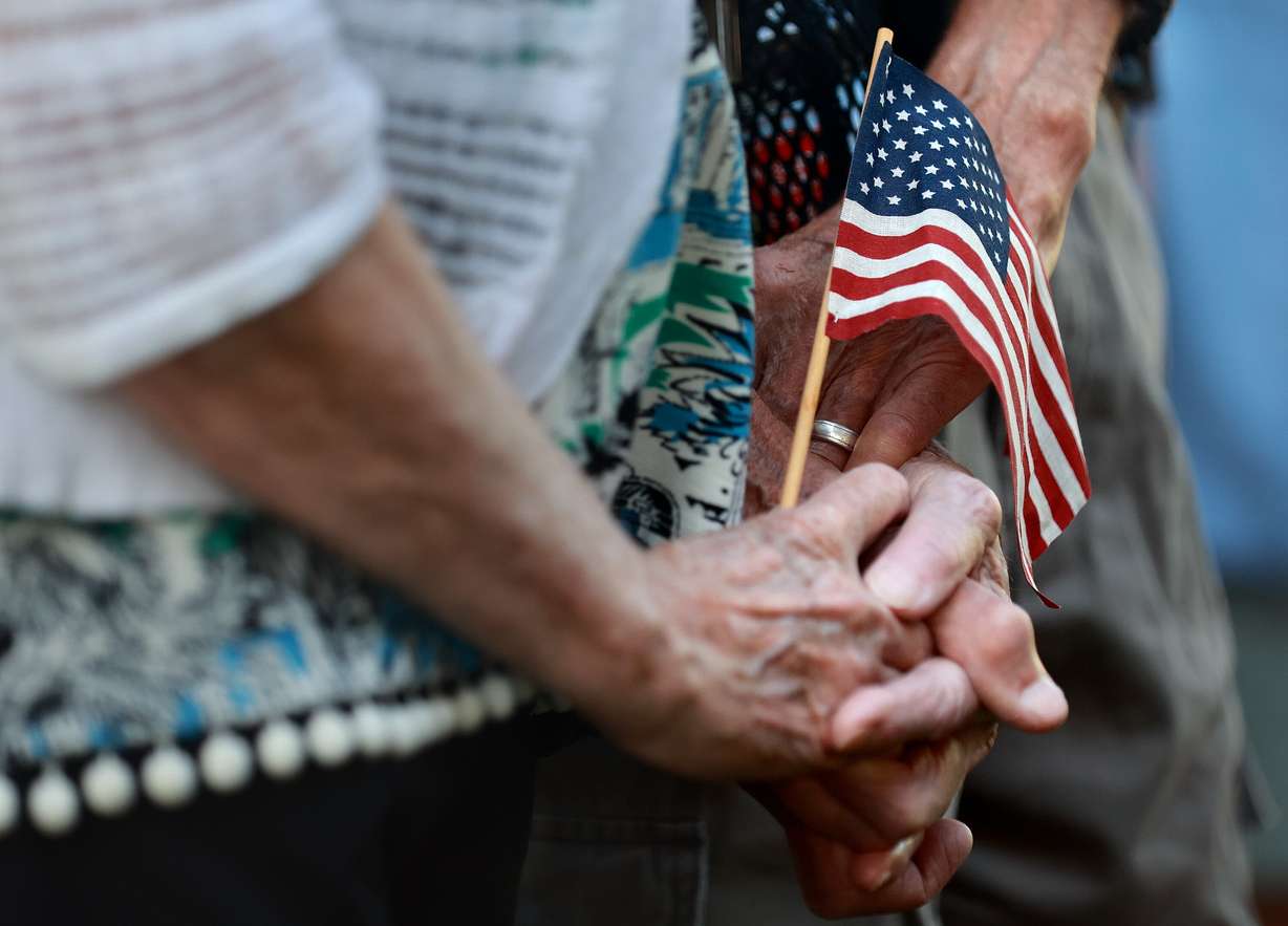 A couple holds an American flag during an ecumenical community prayer gathering called Pray Without Ceasing, held in the wake of the shooting of Charlie Kirk, at Vernon Worthen Park in St. George on Saturday. Tyler Robinson, who is accused of killing Kirk, lives nearby in Washington. Kirk was a conservative activist and the founder and president of Turning Point USA.