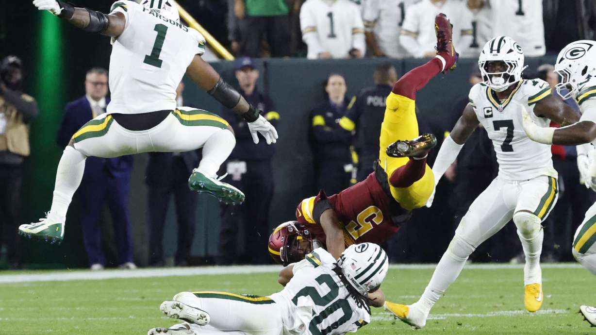 Washington Commanders quarterback Jayden Daniels (5) is upended by Green Bay Packers safety Javon Bullard (20) as Packers defensive lineman Micah Parsons (1) and linebacker Quay Walker (7) watch during the second half of an NFL football game Thursday, Sept. 11, 2025, in Green Bay, Wis.