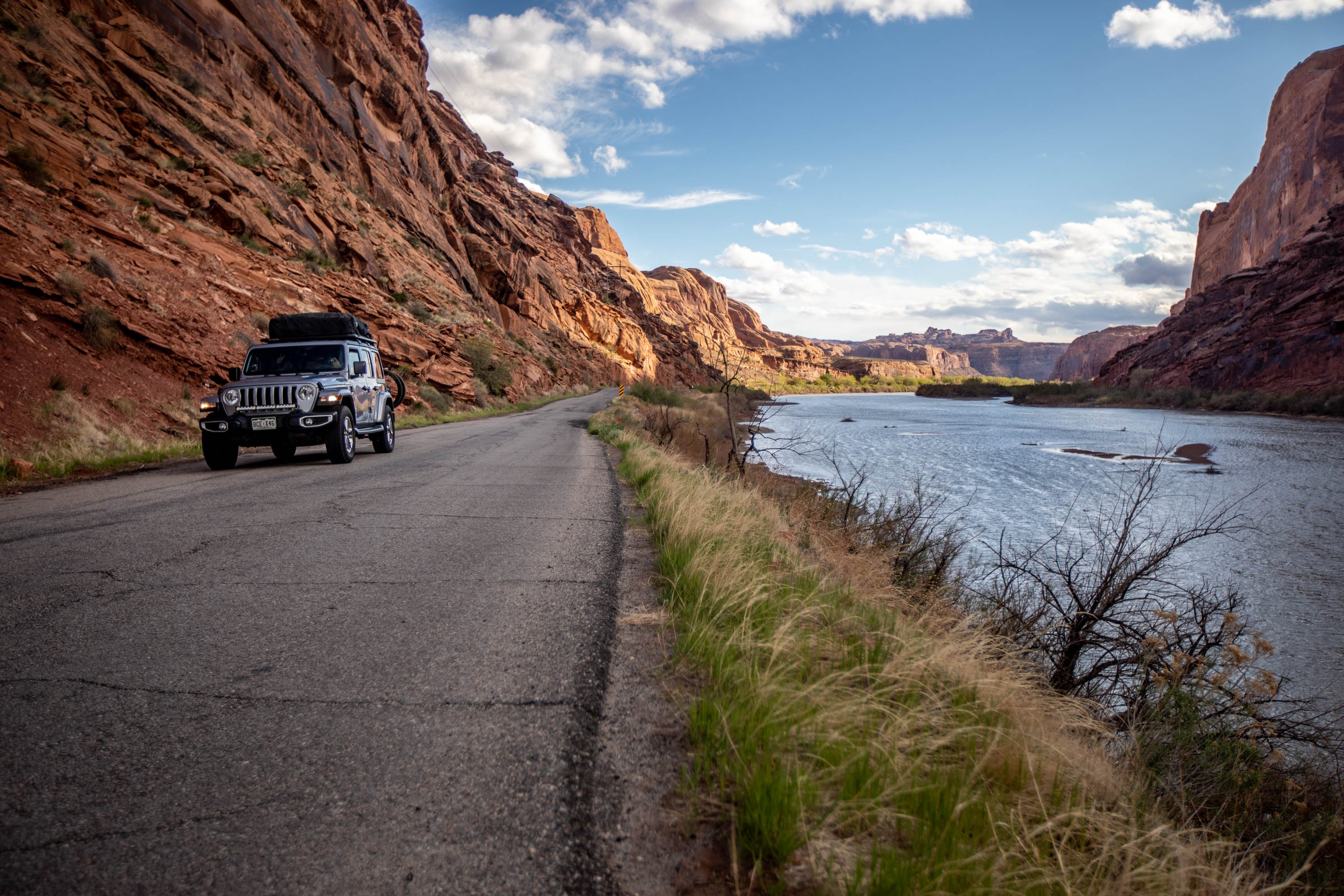 Visitors travel along Kane Creek, a curving asphalt road nestled between the Colorado River and red rock cliffs in Moab on April 16, 2021. The road is in need of repair.