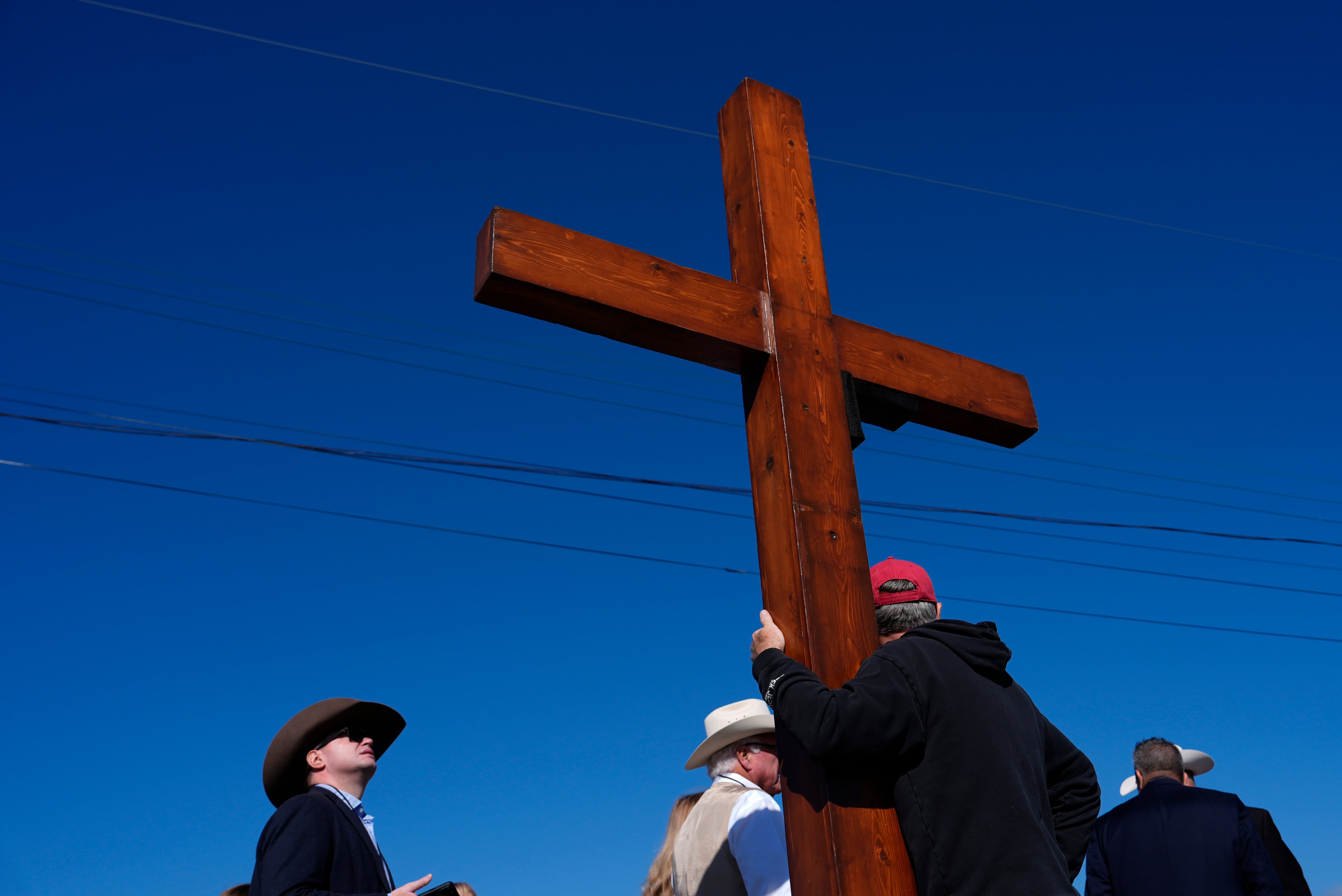 Dan Beasley of Northville, Mich., holds a cross before Republican presidential nominee former President Donald Trump speaks at a campaign rally at the Butler Farm Show, the site where a gunman tried to assassinate him in July, Oct. 5, 2024, in Butler, Pa.
