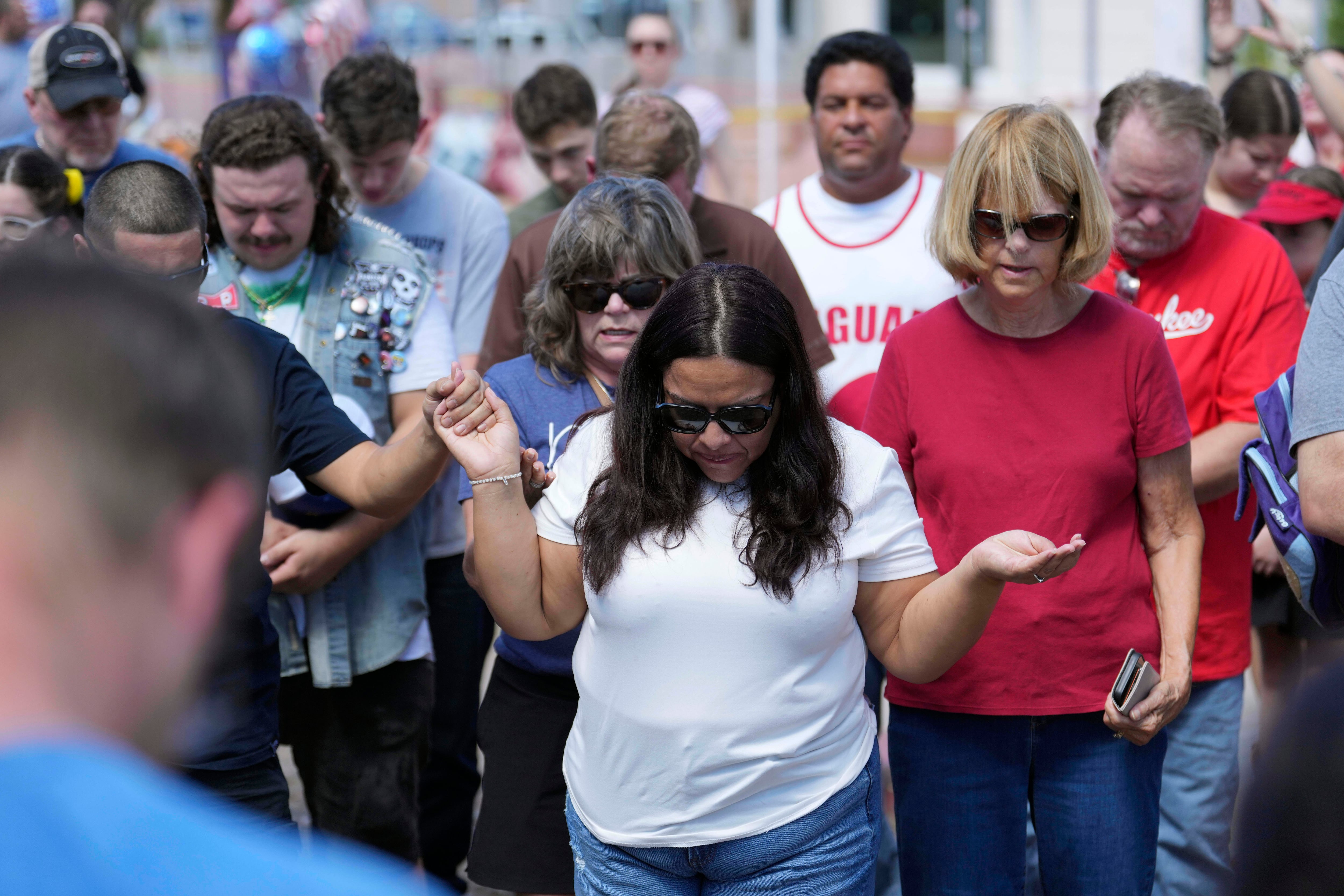 People pray at a makeshift memorial set up at Turning Point USA headquarters after the shooting death at a Utah college on Wednesday of Charlie Kirk, the 31-year-old founder and CEO of the organization, Thursday in Phoenix.