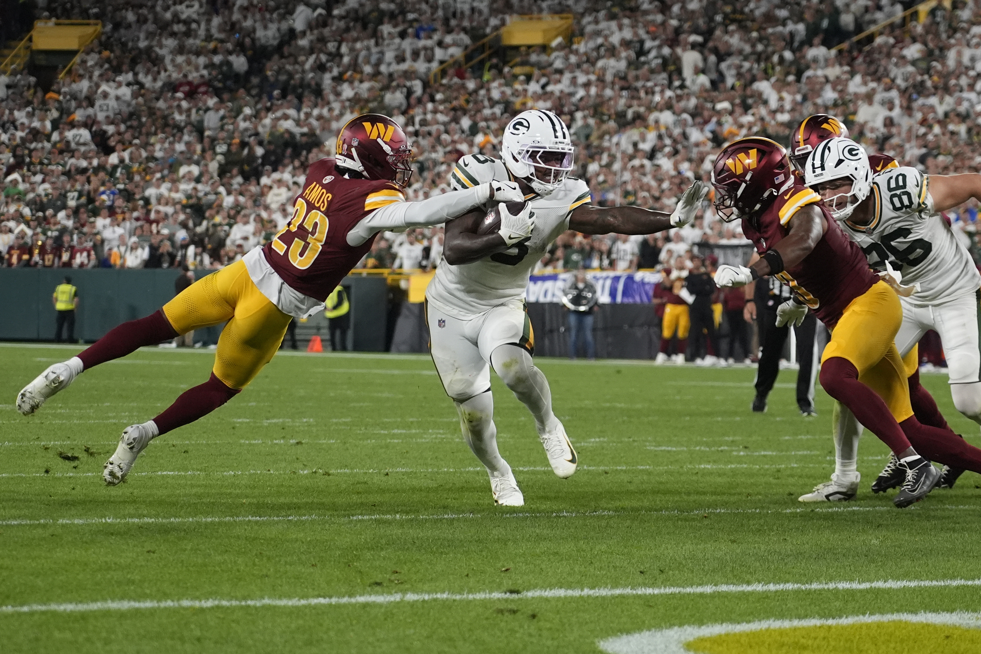 Green Bay Packers running back Josh Jacobs runs with the ball as Washington Commanders cornerback Trey Amos (23) defends during the second half of an NFL football game Thursday, Sept. 11, 2025, in Green Bay, Wis. 