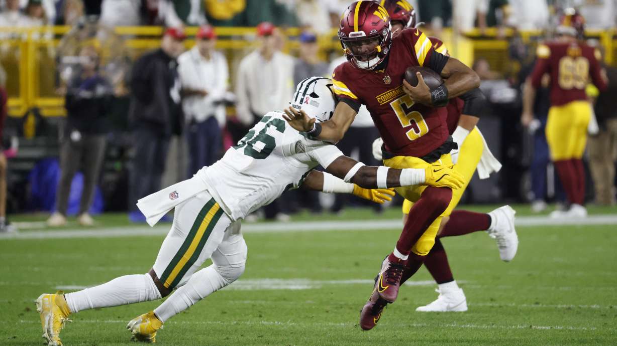 Washington Commanders quarterback Jayden Daniels (5) runs with the ball as Green Bay Packers linebacker Edgerrin Cooper (56) defends during the first half of an NFL football game Thursday, Sept. 11, 2025, in Green Bay, Wis.