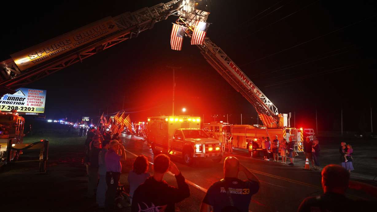 People salute during a procession Wednesday in Spring Grove, Pa. Three police officers were fatally shot and two were wounded Wednesday in southern Pennsylvania, and the shooter was killed by police, authorities said.