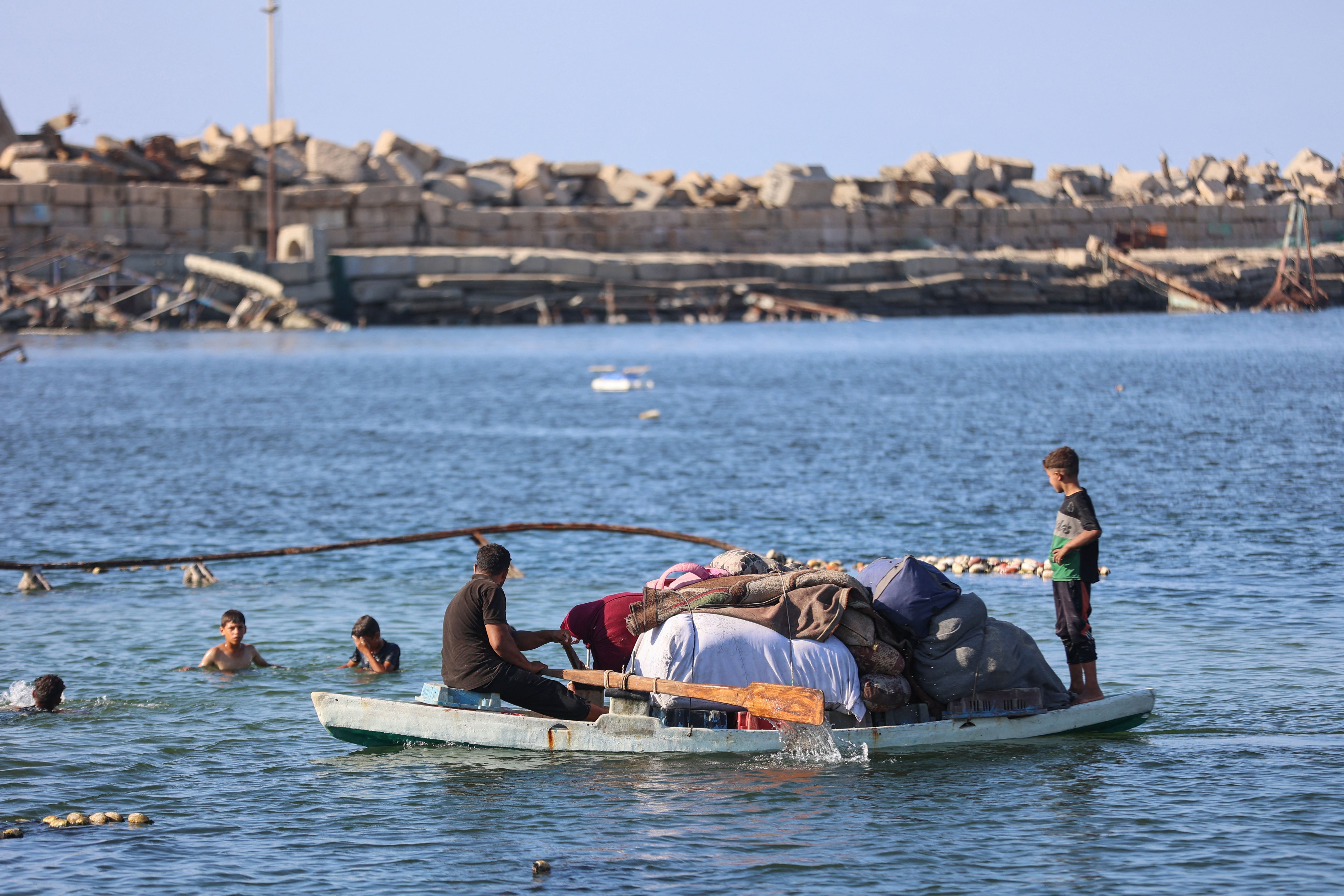 Displaced Palestinians transport their belongings on their fishing board as they flee Israeli bombardment southward, by sea from the Gaza City port on Thursday.